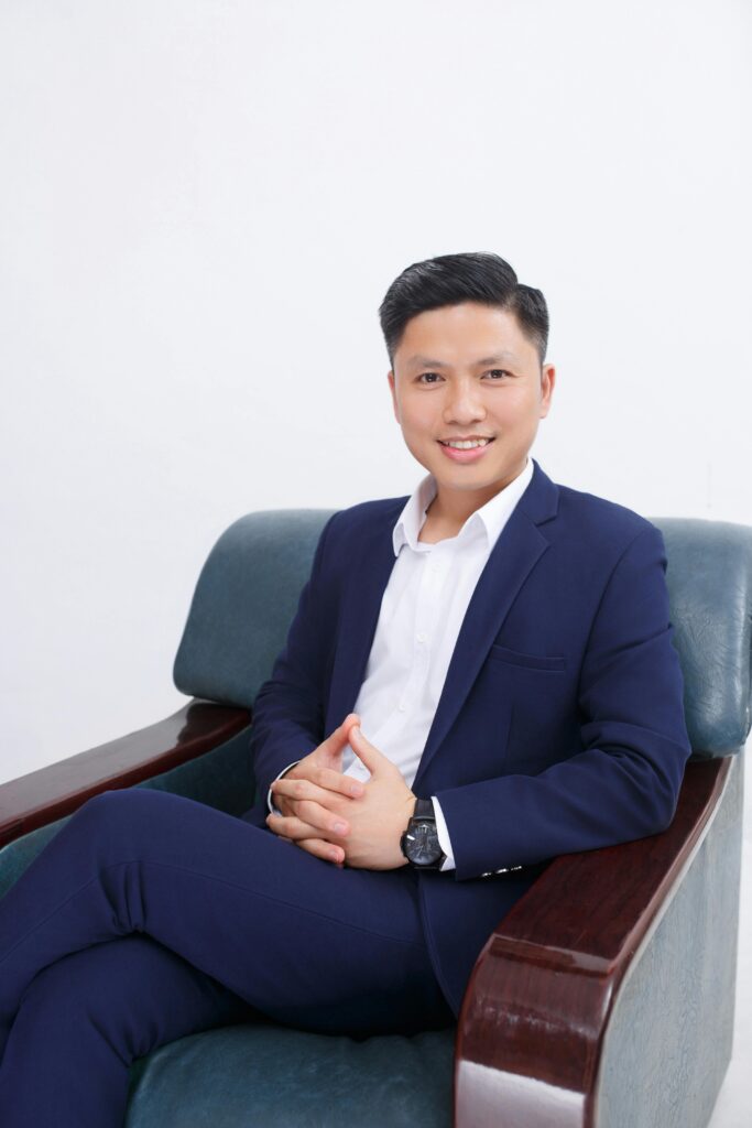 Portrait of a smiling businessman in a blue suit seated comfortably on a chair.